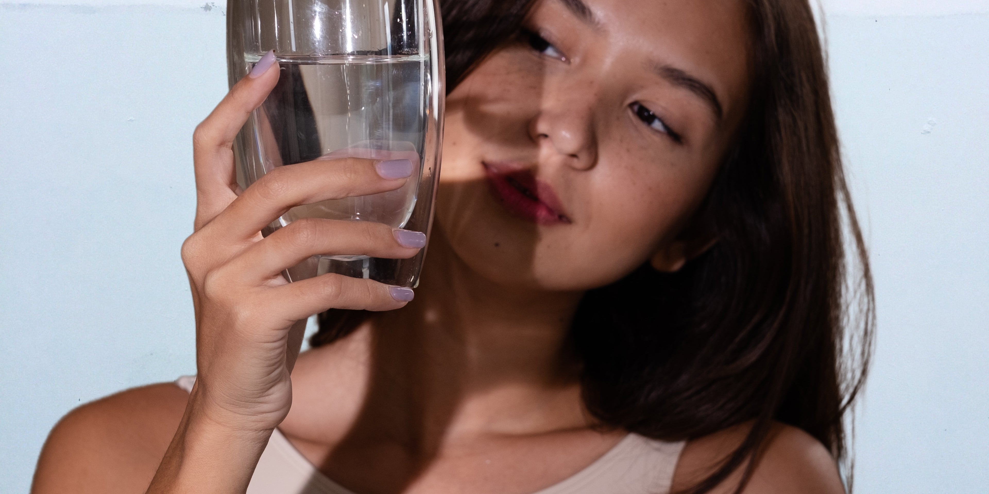 une femme asiatique qui regarder un verre d'eau