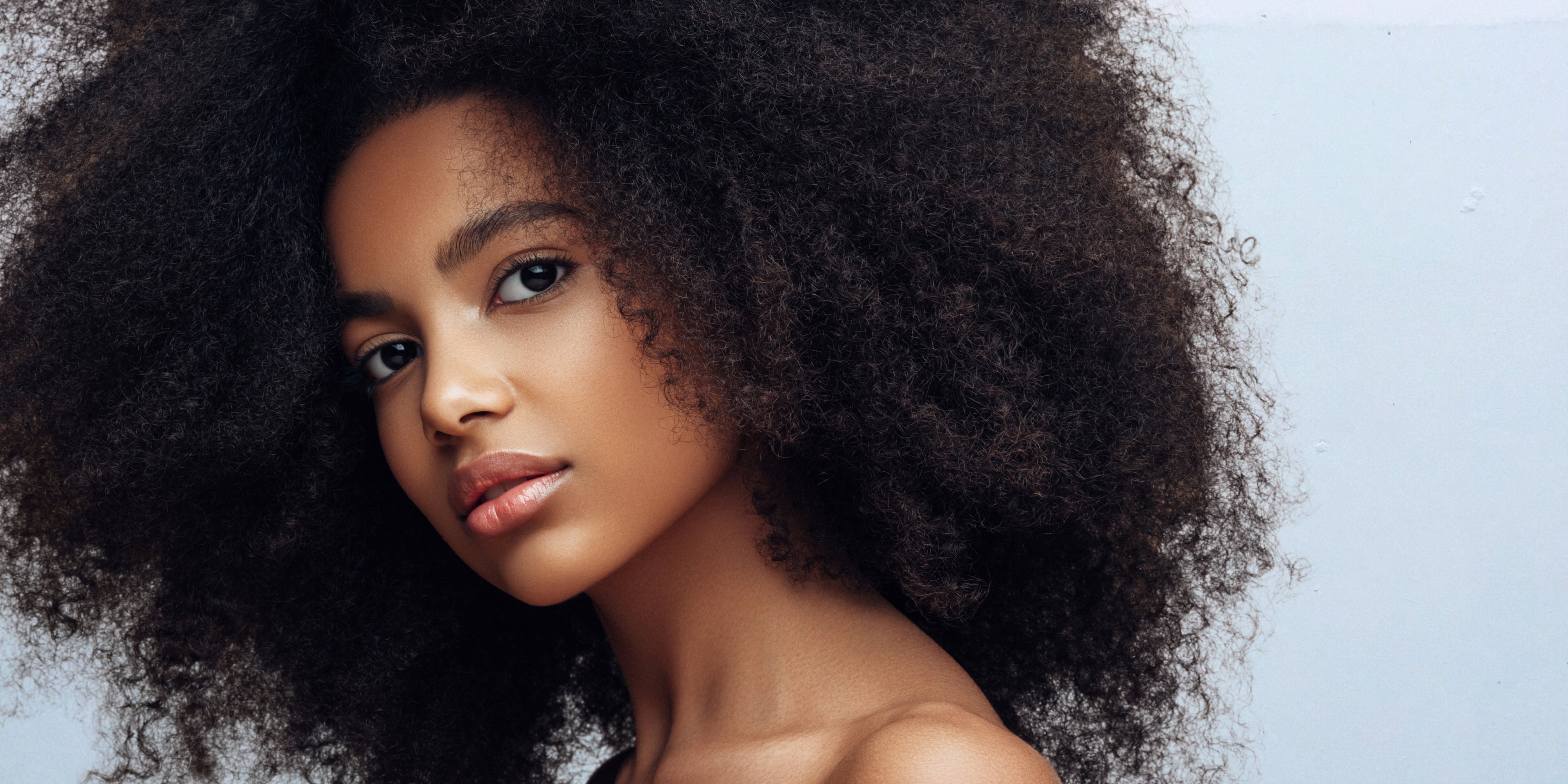 une femme noire avec ses cheveux naturels qui regarde à la caméra